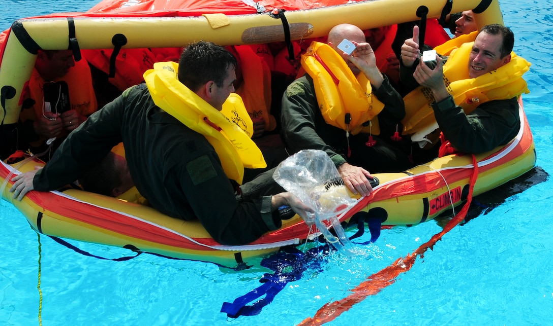 Aircrew members practice using emergency signaling mirrors during water survival training on Joint Base Andrews, Md., as part of survival, evasion, resistance, and escape training, June 19, 2014. The training focuses on evading capture, survival skills, and the military code of conduct. SERE is mandatory for aircrew and personnel required to maintain Code of Conduct Continuation Training. Skills gained at SERE are tailored for specific aircraft, missions and deployed locations.  (U.S. Air Force photo/Senior Airman Mariah Haddenham )