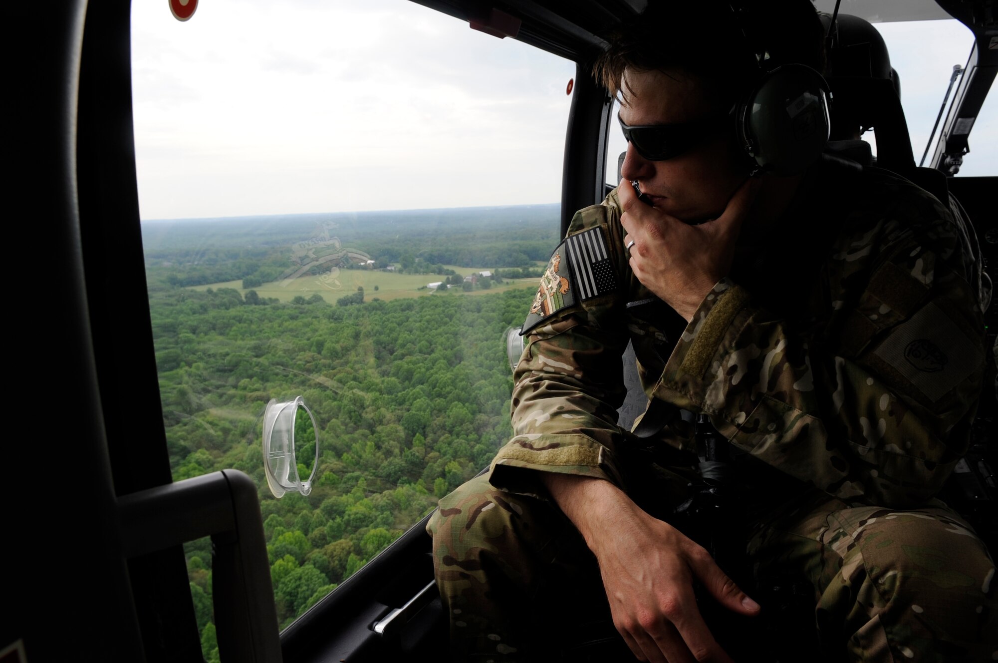 Staff Sgt. Matthew Fistler, 89th Operations Support Squadron survival, evasion, resistance, and escape training NCO in charge stares out the window of a UH-72A Lakota helicopter during SERE in Gambrills, Md.,  June 6, 2014.  The training focuses on evading capture, survival skills, and the military code of conduct. SERE is mandatory for aircrew and personnel required to maintain Code of Conduct Continuation Training. Skills gained at SERE are tailored for specific aircraft, missions and deployed locations.  (U.S. Air Force photo/Senior Airman Mariah Haddenham )