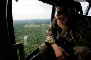 Staff Sgt. Matthew Fistler, 89th Operations Support Squadron survival, evasion, resistance, and escape training NCO in charge stares out the window of a UH-72A Lakota helicopter during SERE in Gambrills, Md.,  June 6, 2014.  The training focuses on evading capture, survival skills, and the military code of conduct. SERE is mandatory for aircrew and personnel required to maintain Code of Conduct Continuation Training. Skills gained at SERE are tailored for specific aircraft, missions and deployed locations.  (U.S. Air Force photo/Senior Airman Mariah Haddenham )