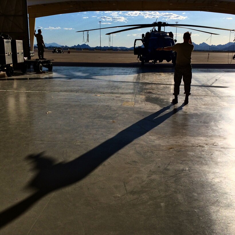Tech Sgt. Peter Muntean guides an HH-60G Pave Hawk helicopter into a hangar at Davis-Monthan Air Force Base, Ariz., June 19, 2014. (U.S. Air Force photo/2nd Lt. Anna-Marie Wyant)