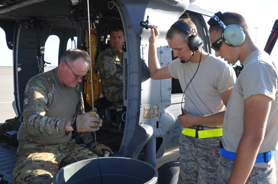 Master Sgt. Ed Dawson (left), a special mission aviator with the 305th Rescue Squadron, Davis-Monthan Air Force Base, Ariz., checks the hoist on an HH-60G Pave Hawk helicopter prior to an air-refueling exercise June 19, 2014. Senior Airman Ryan Jutting (second right), Airman 1st Class Michael Kramer (right), both tactical aircraft maintainers, and Tech. Sgt. Anthony Truesdale (second left), a special missions aviator, watch Dawson complete the hoist check. An HH-60G's hoist is capable of lifting a 600-pound load from a hover height of 200 feet. (U.S. Air Force photo/Senior Airman Natasha Dowridge)