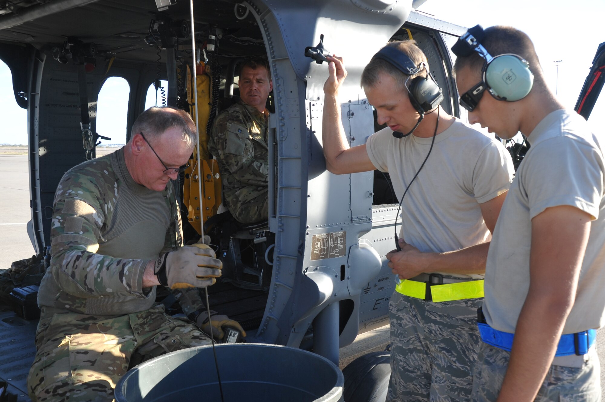 Master Sgt. Ed Dawson (left), a special mission aviator with the 305th Rescue Squadron, Davis-Monthan Air Force Base, Ariz., checks the hoist on an HH-60G Pave Hawk helicopter prior to an air-refueling exercise June 19, 2014. Senior Airman Ryan Jutting (second right), Airman 1st Class Michael Kramer (right), both tactical aircraft maintainers, and Tech. Sgt. Anthony Truesdale (second left), a special missions aviator, watch Dawson complete the hoist check. An HH-60G's hoist is capable of lifting a 600-pound load from a hover height of 200 feet. (U.S. Air Force photo/Senior Airman Natasha Dowridge)