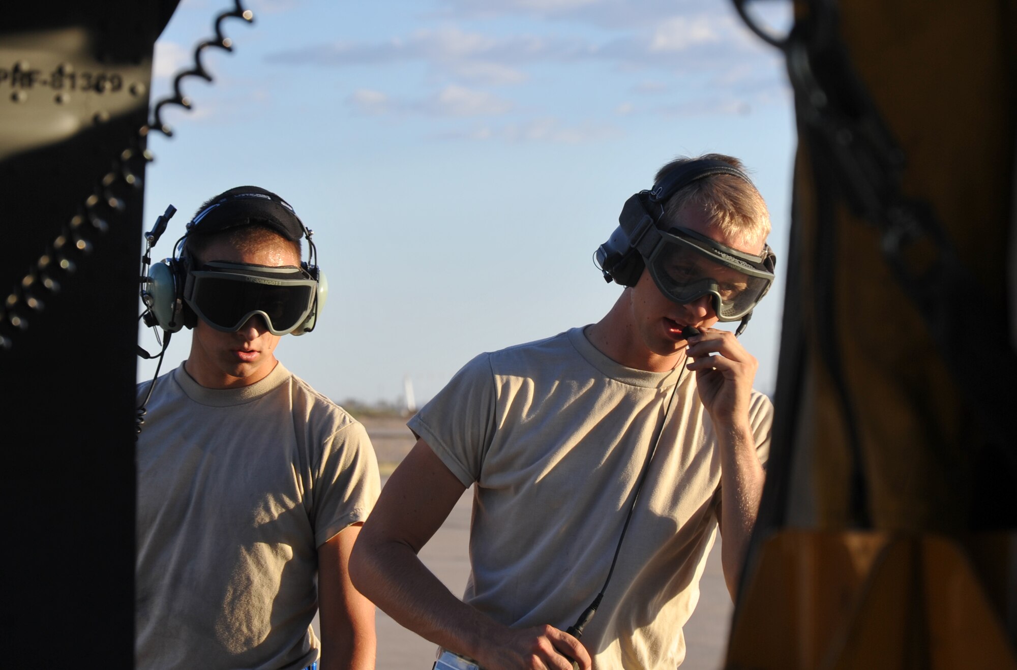 Senior Airman Ryan Jutting (left), a tactical aircraft maintainer with 943rd Rescue Group, Davis-Monthan Air Force Base, Ariz., speaks into his headset to communicate with his fellow tactical aircraft maintainer Airman 1st Class Michael Kramer (right) and the crew members on board an HH-60G Pave Hawk helicopter June 19, 2014. (U.S. Air Force photo/Senior Airman Natasha Dowridge