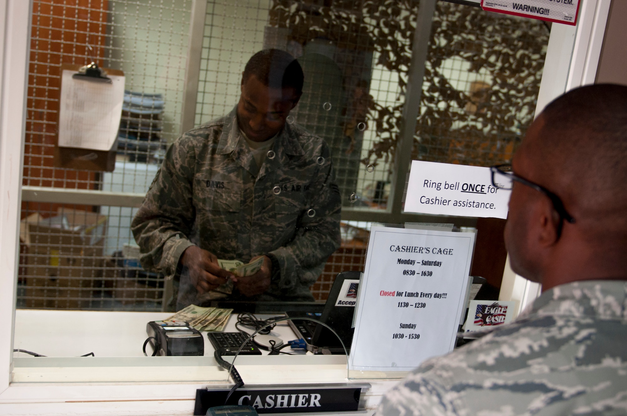 Senior Airman Derrick Davis, 386th Air Expeditionary Wing finance customer service technician and cashier, assists a customer with money exchange at finance at The Rock. Davis deployed from Vandenburg Air Force Base in support of Operation Enduring Freedom and is a native of Lithonia, Georgia. Davis has been deployed here for eight months. (U.S. Air Force photo by Senior Master Sgt. Allison Day)