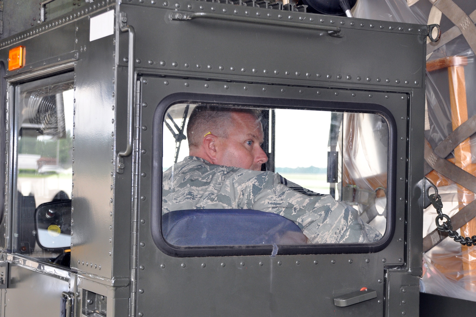 YOUNGSTOWN AIR RESERVE STATION, Ohio – Air Force Reserve Senior Master Sgt. Kevin Massie, superintendent of the 910th Airlift Wing’s 76th Aerial Port Squadron (APS) watches from the cab of a K-Loader ground cargo transport vehicle as members of the APS team move cargo to a waiting C-5 Galaxy strategic cargo transport aircraft on the flightline here, June 13, 2014. The “Port Dawgs,” as Aerial Port Squadrons are nicknamed throughout the Air Force, are loading more than 30 tons of humanitarian cargo onto the aircraft. The cargo is being flown to a pediatric hospice in Guatemala as part of the Denton program which allows non-governmental organizations to utilize military airlift to move their humanitarian cargos to those who need it. U.S. Air Force photo by Master Sgt. Bob Barko Jr.