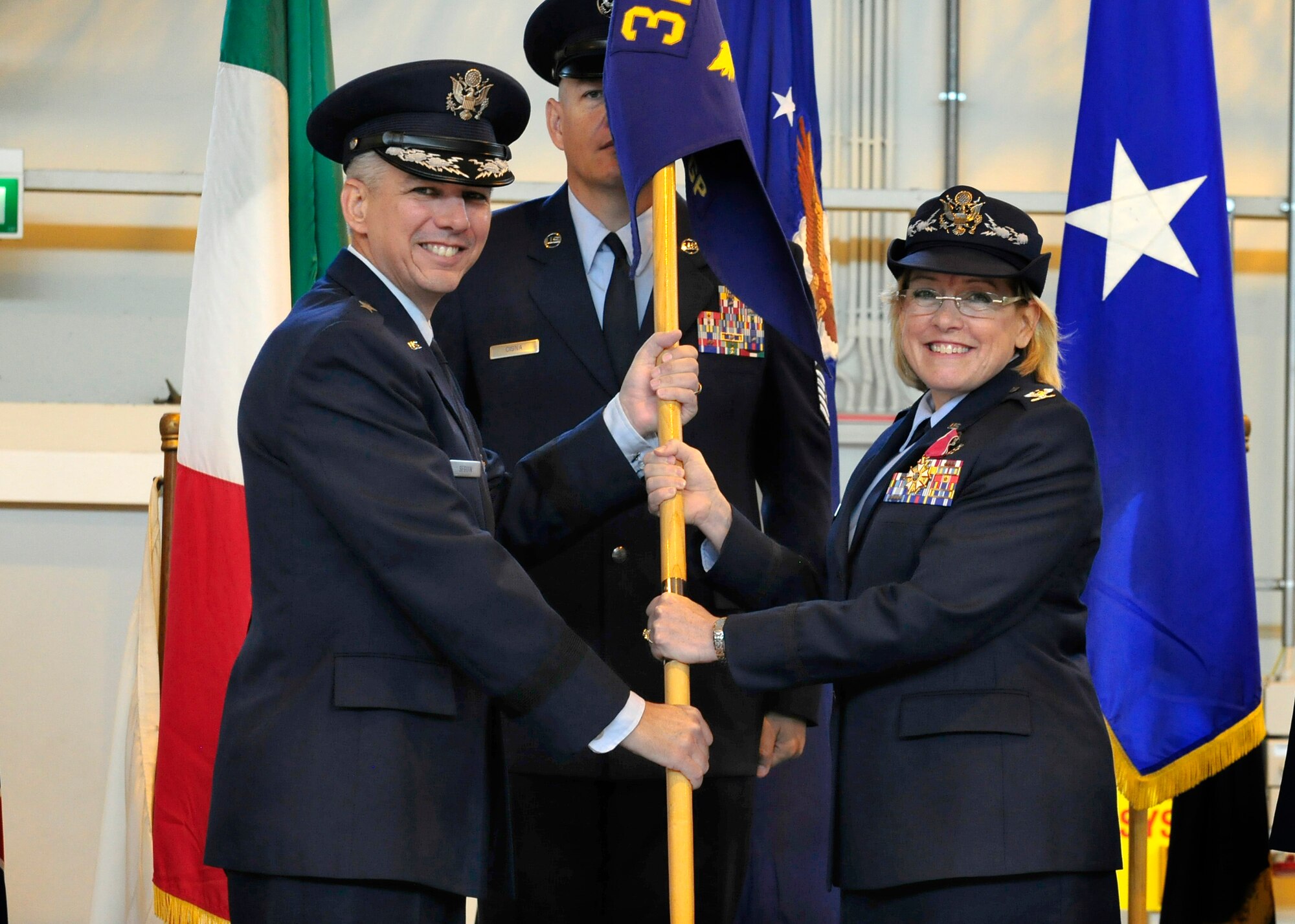 Col. Linda Lawrence passes the 31st Medical Group guidon to Brig. Gen. Barre Seguin, 31st Fighter Wing commander, during the group’s change of command ceremony, June 20, 2014, at Aviano Air Base, Italy. Lawrence served as commander of the 31st MDG for more than three years. (U.S. Air Force photo/Airman 1st Class Ryan Conroy) 
