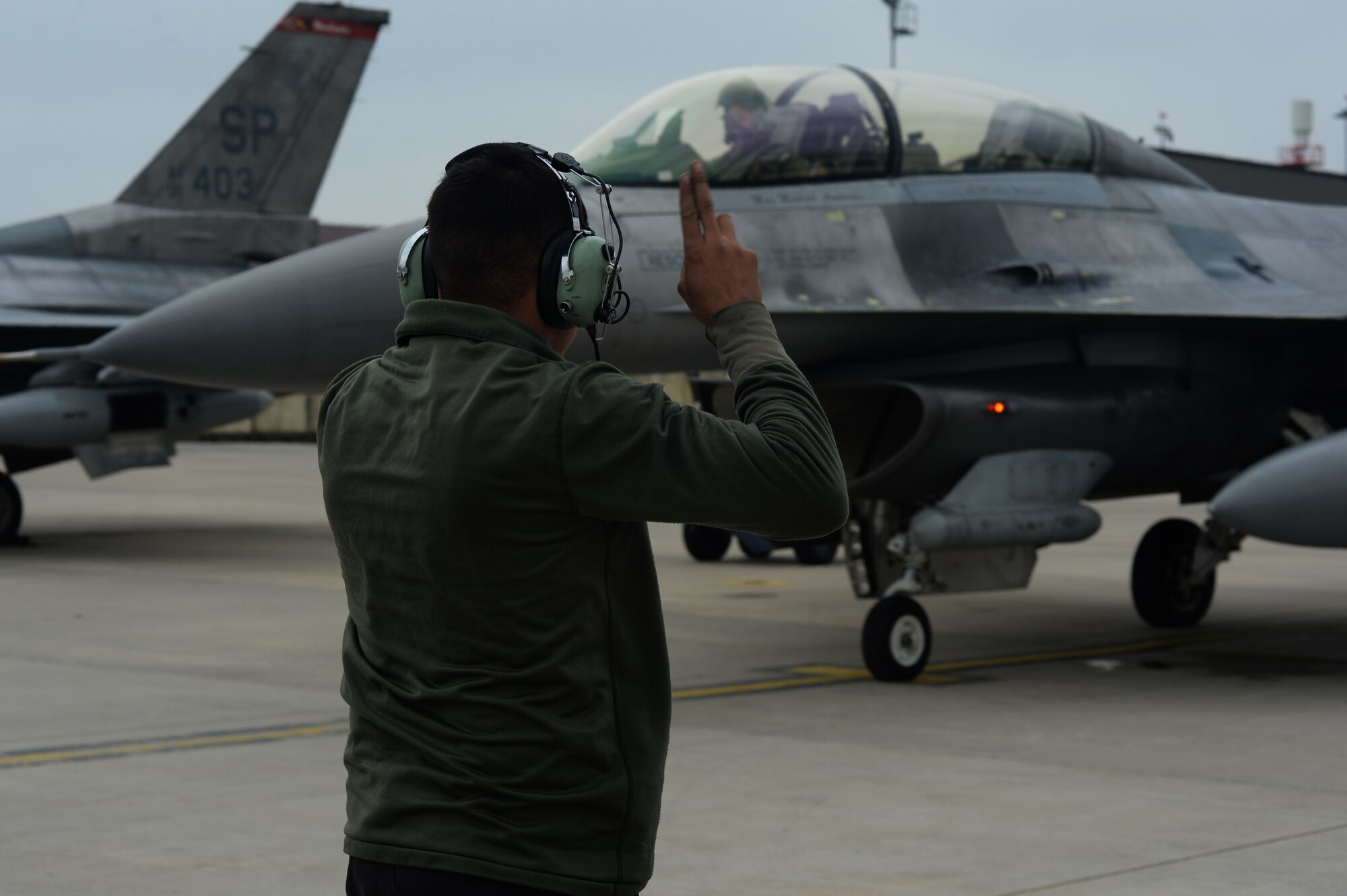 U.S. Air Force Senior Airman Ramiro Gamero, a 480th Aircraft Maintenance Unit crew chief from Riverside, Calif., directs a 480th Fighter Squadron F-16 Fighting Falcon fighter aircraft pilot on the flightline at Spangdahlem Air Base, Germany, May 2, 2014. The squadron regularly sends aircraft to Lask Air Base, Poland, as part of the 52nd Operations Group, U.S. Air Force Aviation Detachment’s rotations.  (U.S. Air Force photo by Staff Sgt. Joe W. McFadden/Released)