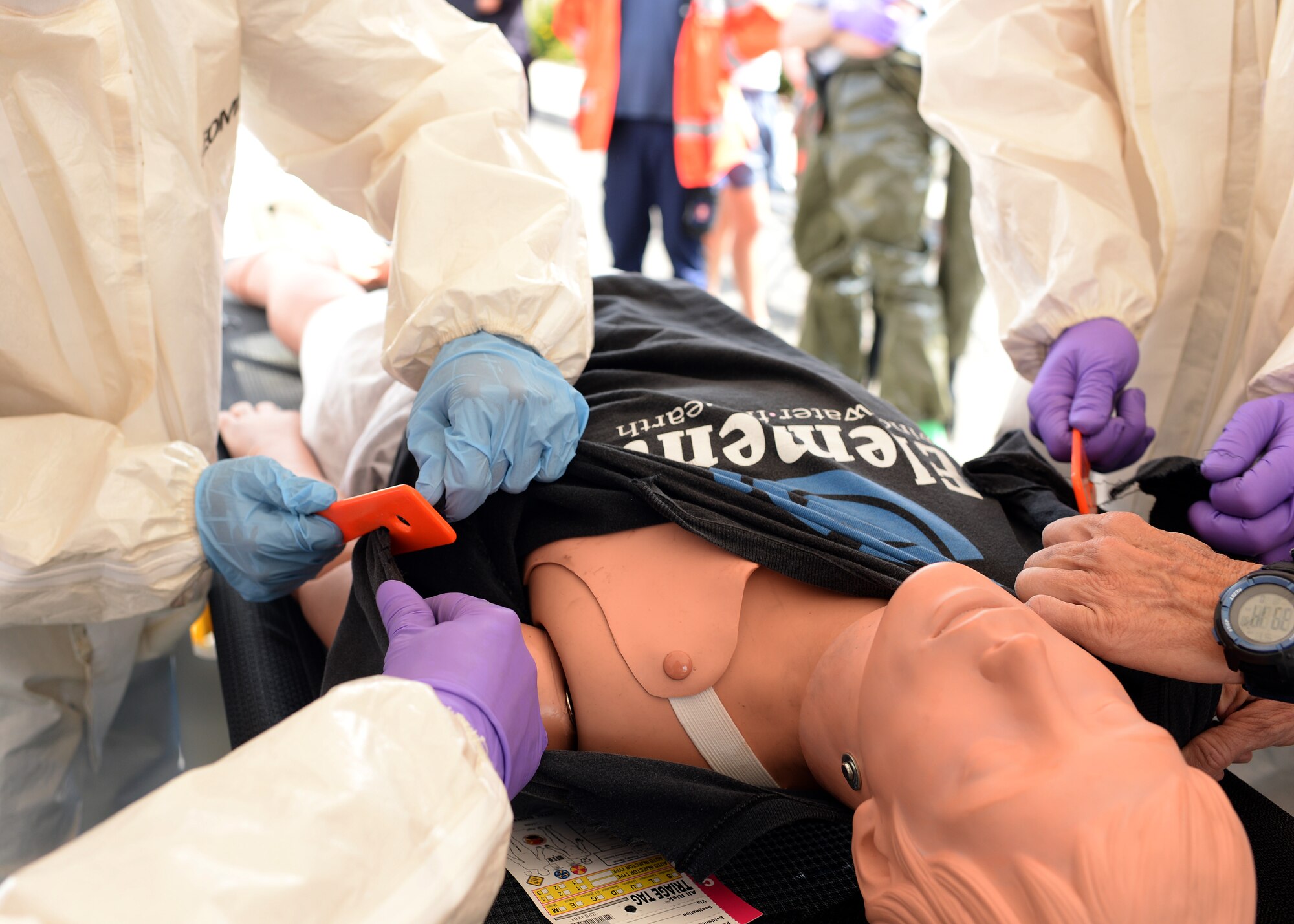 Medics cut away clothing from a mock patient during a training event June 18, 2014, at Spangdahlem Air Base, Germany. Contaminants can cover an individual’s entire body, so the medical team removes all the exterior items — such as clothing and jewelry — before cleaning the patient. (U.S. Air Force photo by Staff Sgt. Daryl Knee/Released)