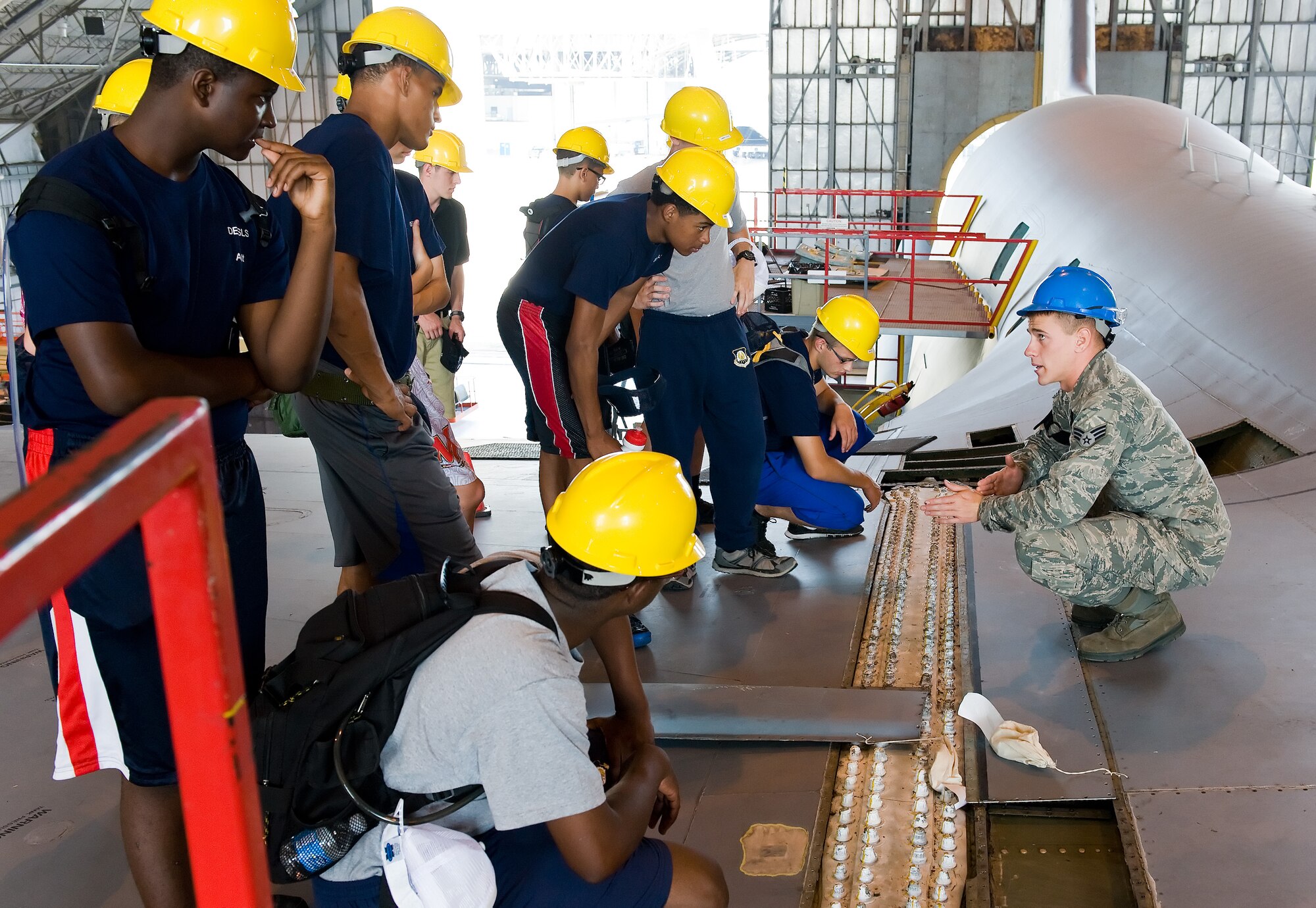 Senior Airman Alexander King, right, 436th Maintenance Squadron aerospace maintenance technician, shows Air Force junior ROTC cadets the C-5B Galaxy right wing inner slice bolts June 18, 2014, at the isochronal inspection hangar on Dover Air Force Base, Del. The cadets were briefed on the C-5B isochronal inspection process and toured around the aircraft. (U.S. Air Force photo/Roland Balik)