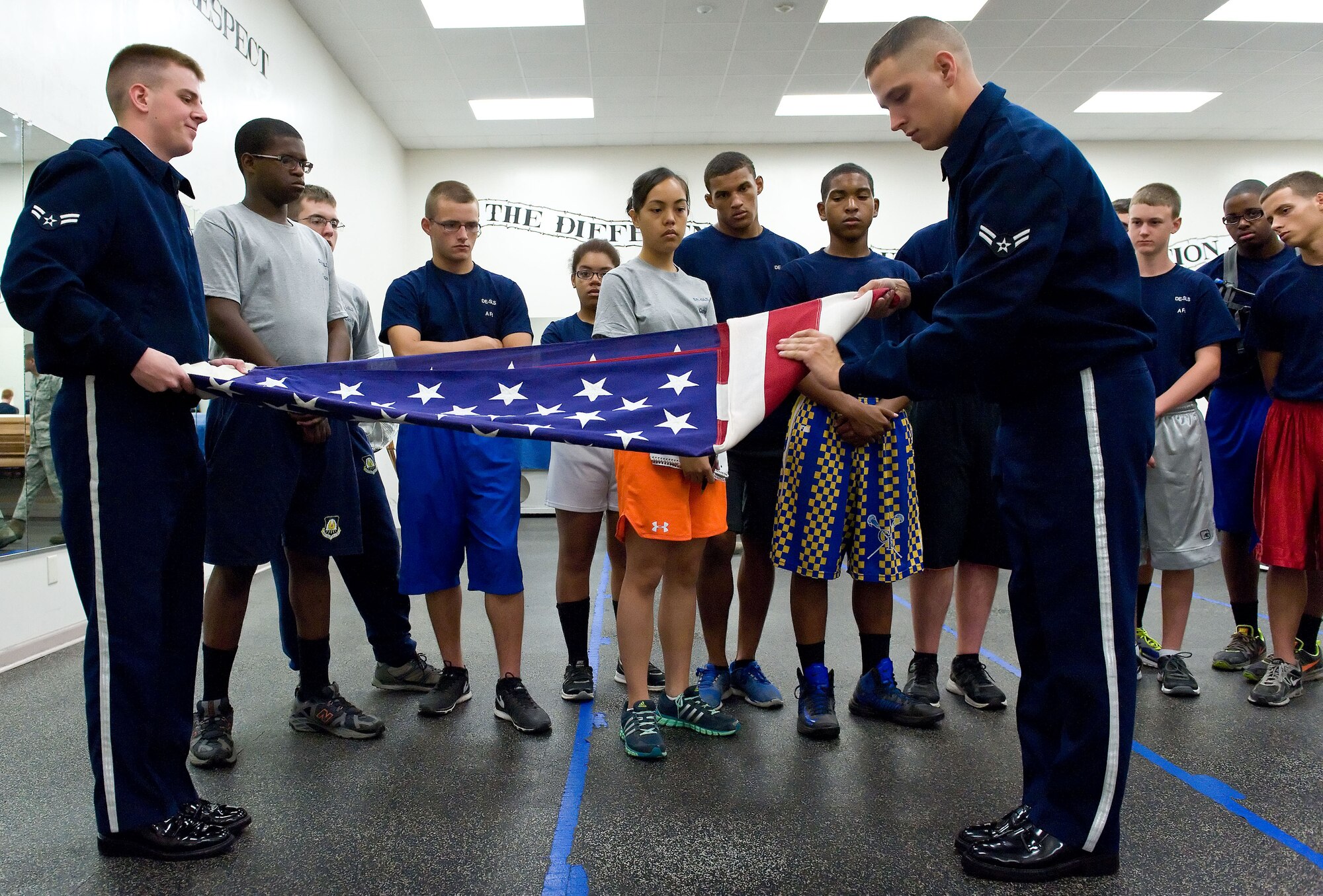 Airman 1st Class Jacob Lassiter, left, and Steven Sanford, right, both Dover Air Force Base honor guard members, fold the U.S. flag June 18, 2014, at Dover AFB, Del. Lassiter and Sanford demonstrated ceremonial flag-folding techniques for Air Force junior ROTC cadets from local Delaware high schools. (U.S. Air Force photo/Roland Balik)
