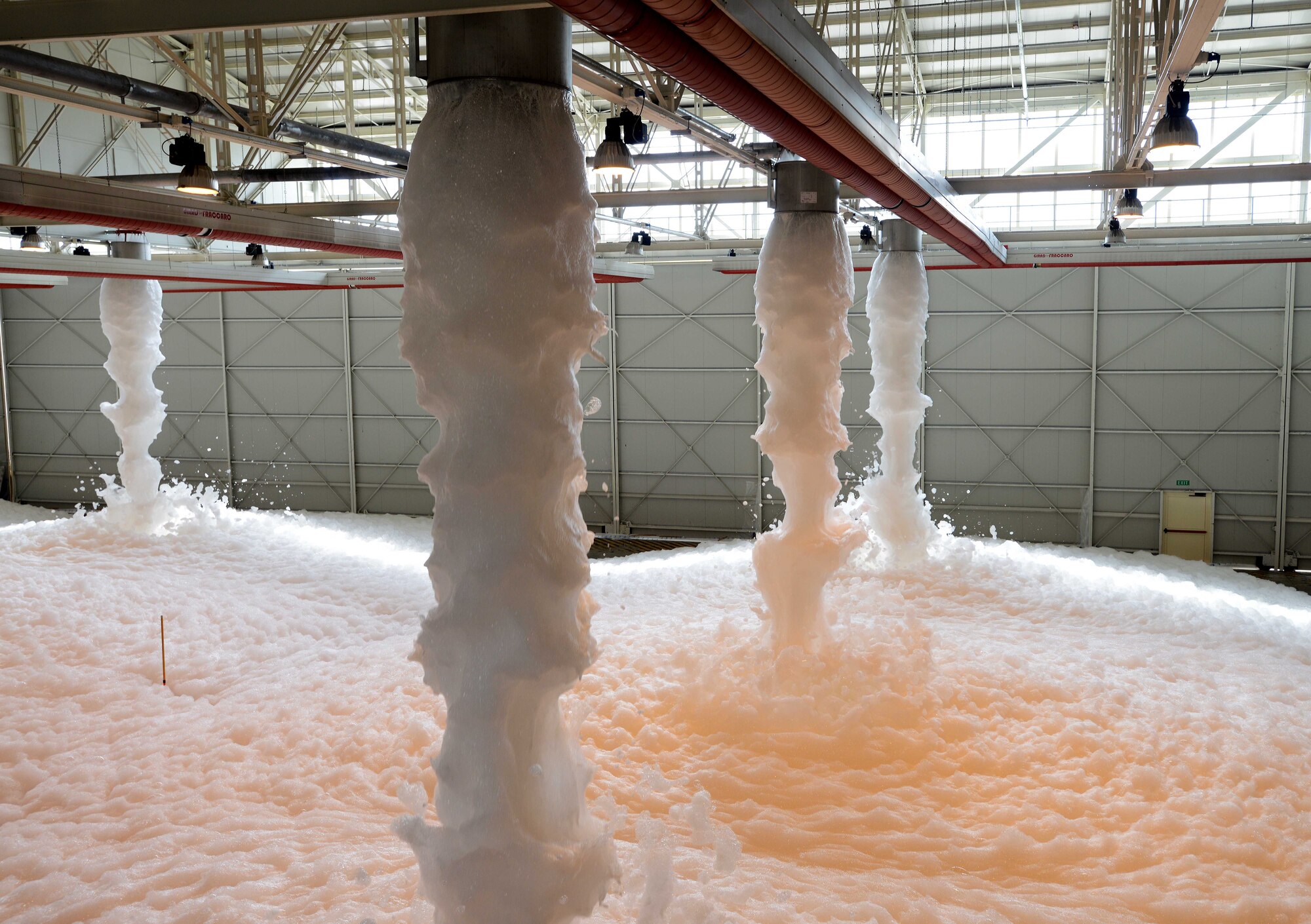 Foam falls to the ground during a fire suppression test, June 18, 2014, at Aviano Air Base, Italy. The biodegradable foam solution is consisted of water, high expansion foam and air, which works to smother flames and prevent reigniting. Leftover foam is dissipated by running water through the generators; from there, Airmen sweep the left over water and foam out of the hangar. (U.S. Air Force photo/Airman 1st Class Deana Heitzman)