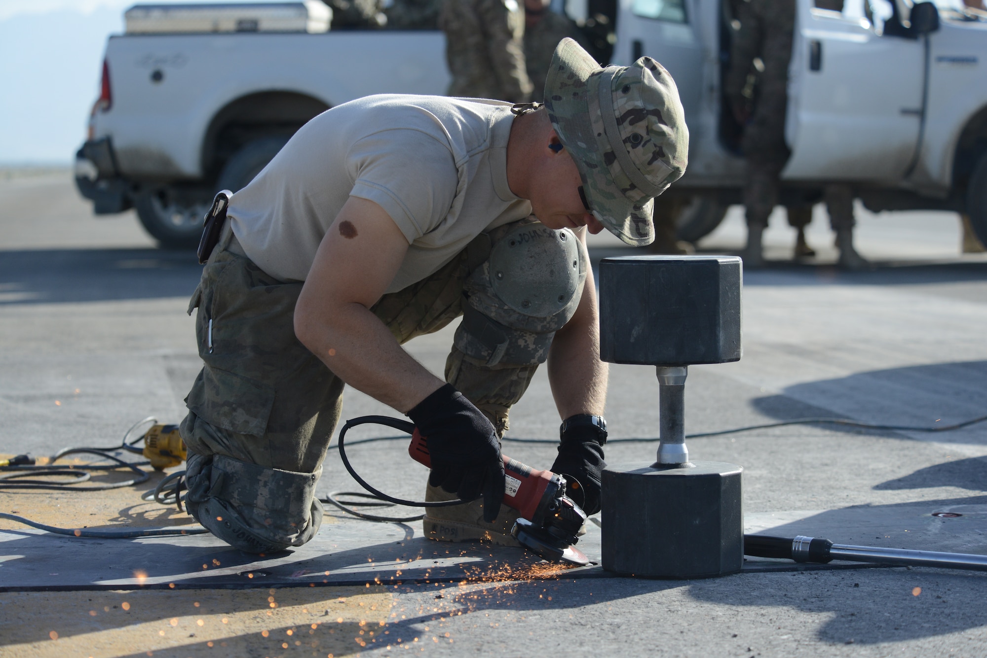 U.S. Air Force Tech. Sgt. James Johnson, a structures craftsman assigned to the 455th Expeditionary Civil Engineer Squadron grinds the top of a bolt securing a poly panel on the flight line of Bagram Airfield, Afghanistan June 8, 2014. Johnson grinds down the bolts to keep them from interfering with takeoff and landing procedures. More than 500 bolts out of 992 were replaced due to improper installatio procedures by a previous contractor. Johnson is deployed from the 142nd Air National Guard in Portland, Ore. (U.S. Air Force photo by Master Sgt. Cohen A. Young/Released)