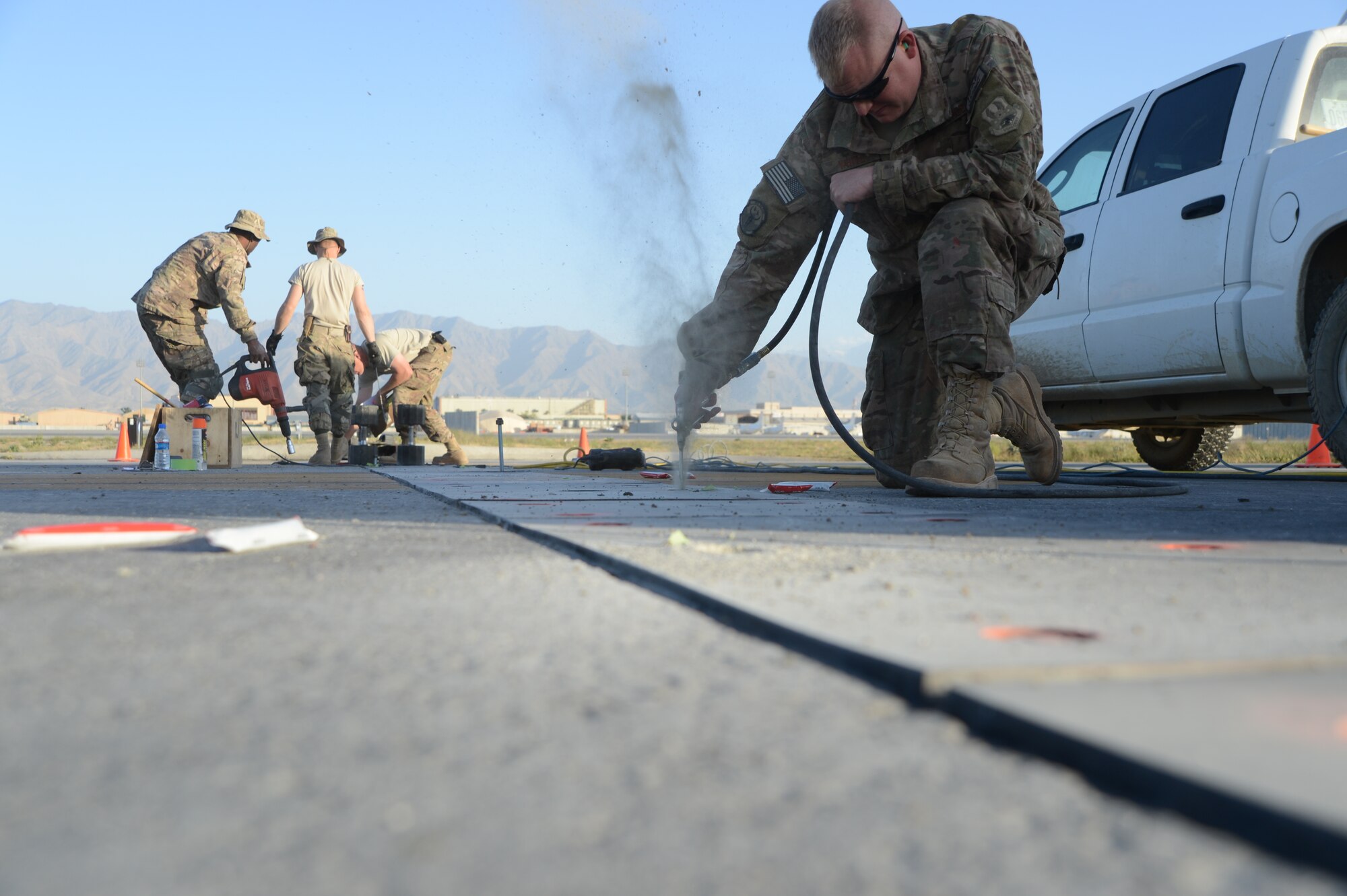 U.S. Air Force Tech. Sgt. C. J. White, a native of Houston, Texas and a heavy equipment operator assigned to the 455th Expeditionary Civil Engineer Squadron clears out dusts and rocks in a hole that will be used to install bolts in the ground to hold poly panels in place to secure aircraft arresting system cables at Bagram Airfield, Afghanistan June 8, 2014. Airmen replaced 502 bolts on the flight line. White is deployed from the 147th Reconnaissance Wing, Texas Air National Guard, Ellington Field Joint Reserve Base, Houston, Texas. (U.S. Air Force photo by Master Sgt. Cohen A. Young/Released)