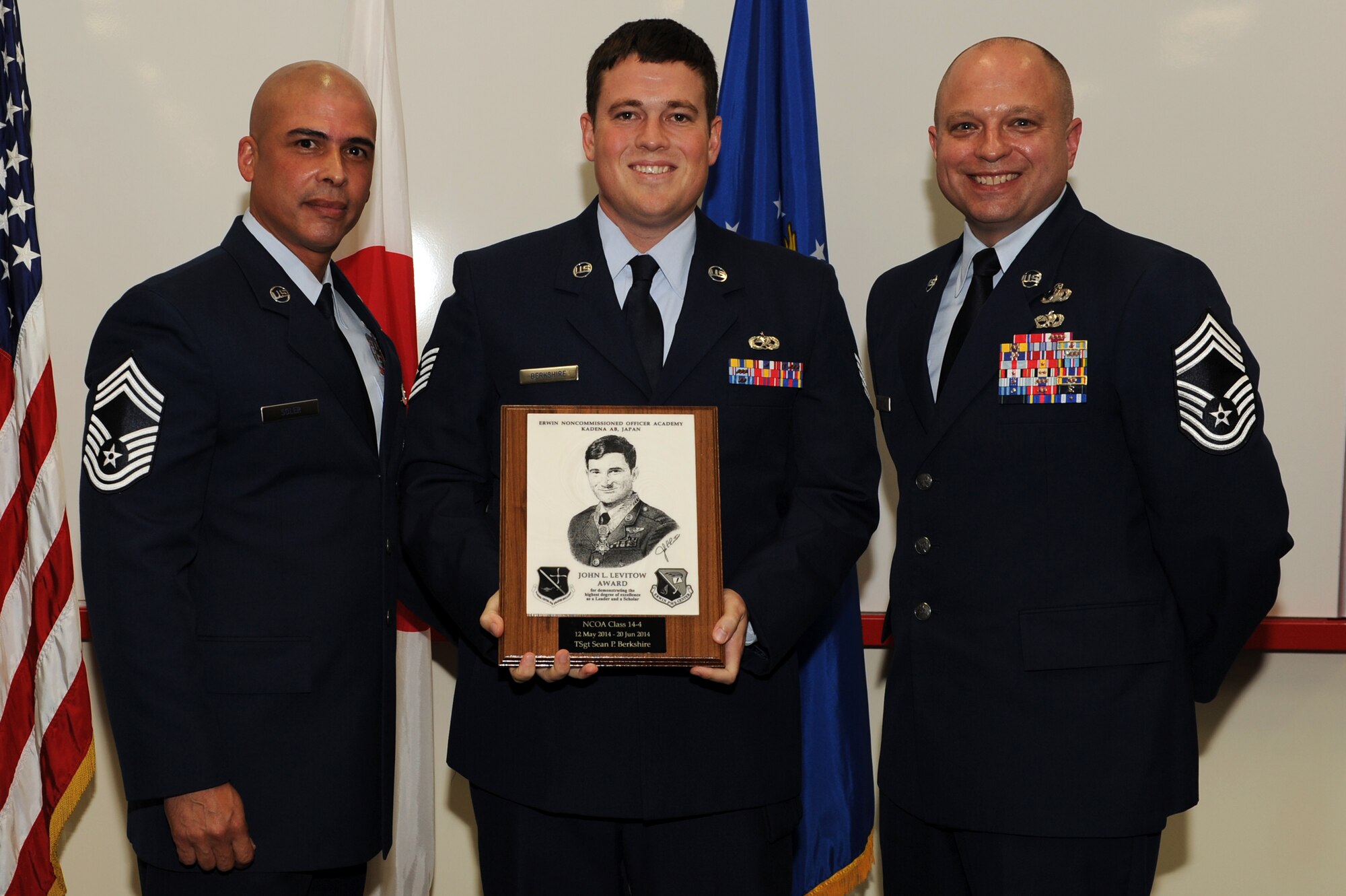 U.S. Air Force Chief Master Sgt. Hector Soler, 18th Security Forces Squadron security forces manager (left), and Chief Master Sgt. Jeffrey Martin, 18th Mission Support Group superintendent (right), present Tech. Sgt. Sean Berkshire, assigned to the 718th Aircraft Maintenance Squadron, the John L. Levitow Award during the NCO Academy class 14-4 graduation ceremony at the Erwin Professional Military Education center on Kadena Air Base, Japan, June 20, 2014. The award, named after Medal of Honor recipient John L. Levitow, is presented to the top performer in the class and is a symbol of achievement as a leader and a scholar. (U.S. Air Force photo by Airman 1st Class Zade C. Vadnais)