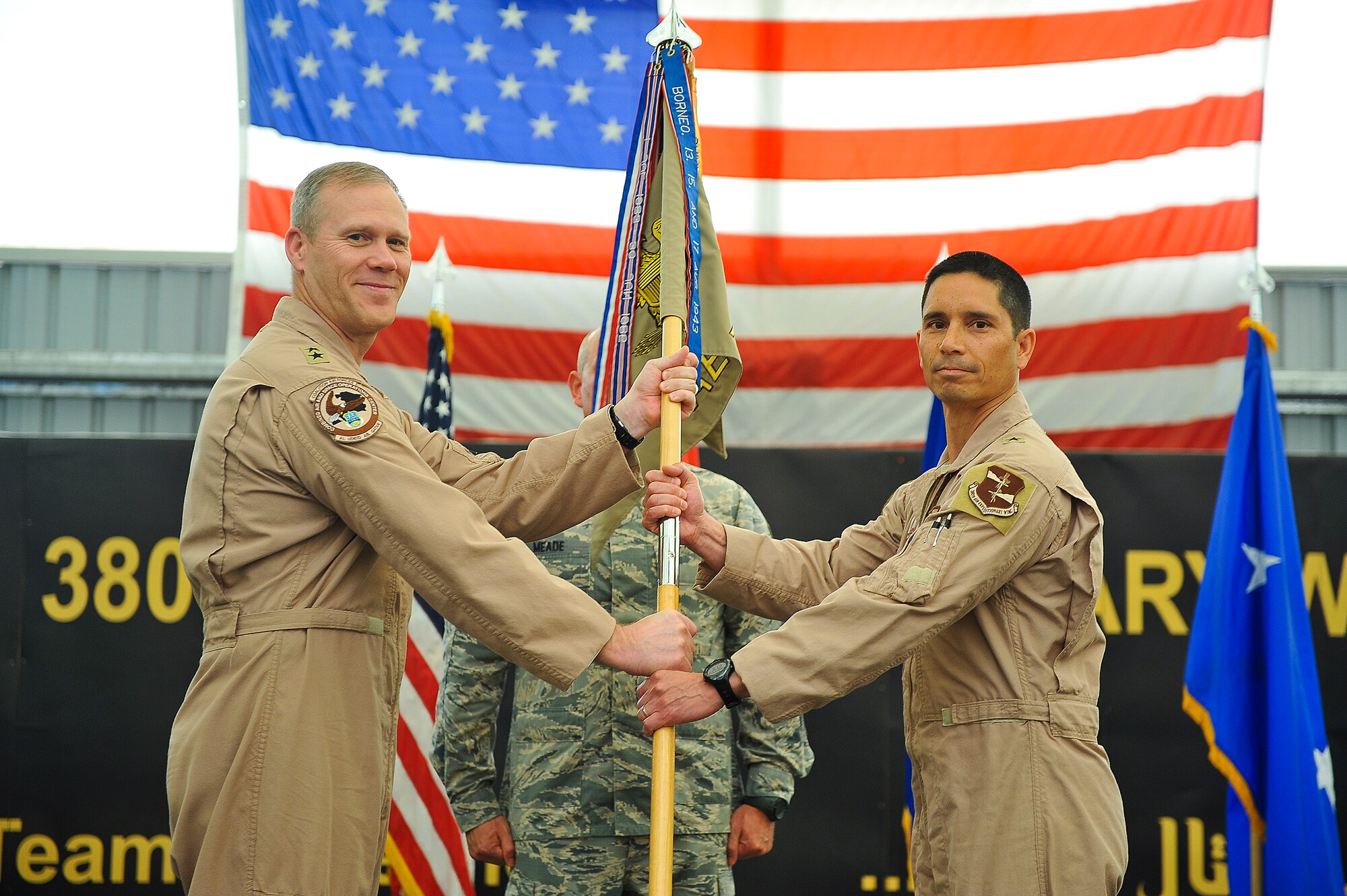 Brig. Gen. John Quintas, 380th Air Expeditionary Wing commander, receives the guidon from Maj. Gen. Jeffrey Lofgren, deputy commander, U.S. Air Forces Central Command and deputy, Combined Forces Air Component Commander, during a change of command ceremony June 18, 2014, at an undisclosed location in Southwest Asia. (U.S. Air Force photo by Tech. Sgt. Russ Scalf/Released)