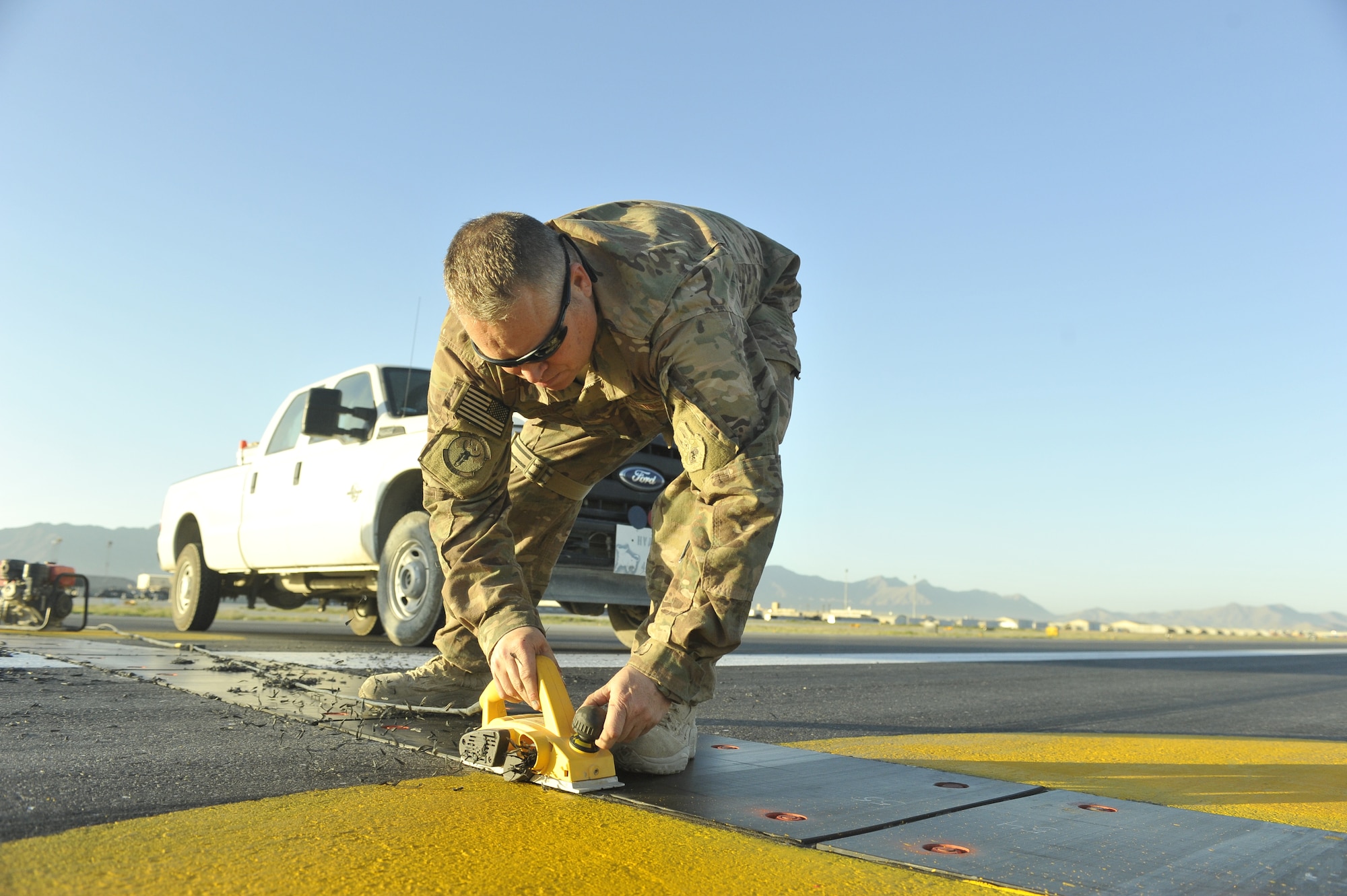 Senior Master Sgt. Douglas Ion, 455th Expeditionary Civil Engineer Squadron project non-commissioned officer in charge, uses a power plainer to remove poly panel material to prevent potential aircraft mishaps on the flightline at Bagram Airfield, Afghanistan June 9th, 2014. Ion is a native of Duluth, Minnesota and is deployed from the Air National Guards' 148th Fighter Wing, Duluth, Minnesota. (U.S. Air Force photo by Airman 1st Class Bobby Cummings/Released)