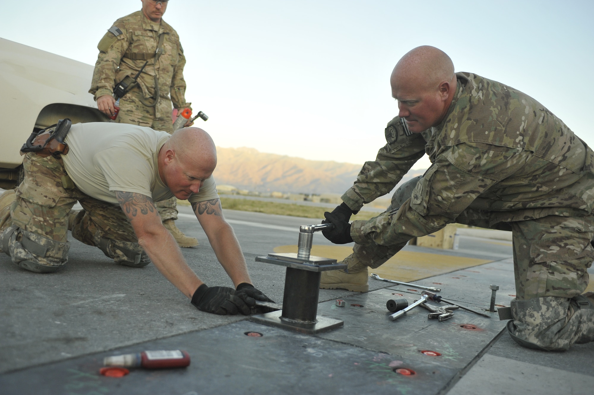 Master Sgt. Joshua Graves (left), 455th Expeditionary Civil Engineer Squadron superintendent, and Master Sgt. Jeremiah Graves, 455th ECES non-commissioned officer in charge of operations, conduct repairs on the main runway at Bagram Airfield, Afghanistan June 9th, 2014. Joshua and Jeremiah, two brothers from Duluth, Minnesota are deployed from the Air National guards' 148th Fighter Wing, Duluth, Minnesota. (U.S. Air Force photo by Airman 1st Class Bobby Cummings/Released)