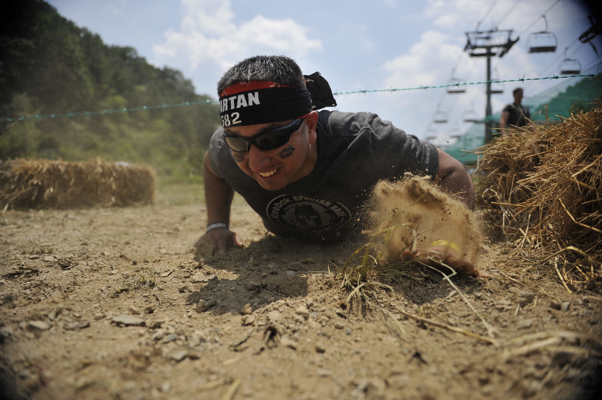 Tech. Sgt. Raynaldo Carrasco, 25th Aircraft Maintenance Unit aerospace propulsion craftsman, crawls through a barbed wire crawl obstacle during a Spartan Race in Seoul, Republic of Korea, June 15, 2014. The wire crawl obstacle can range from 20 to -100 yards in length. (U.S. Air Force photo/Senior Airman David Owsianka)