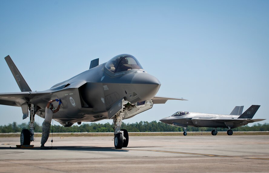 Staff Sgt. Mark Freeman, 33rd Aircraft Maintenance Squadron, opens the fuel panel on an F-35A Lightning II while another Air Force joint strike fighter waits to be refueled at Eglin Air Force Base, Fla.  All of the F-35 variants use the “hot pit” refueling areas in conjunction with the 96th Logistics Readiness Squadron’s fuels flight.  (U.S. Air Force photo/Samuel King Jr.)