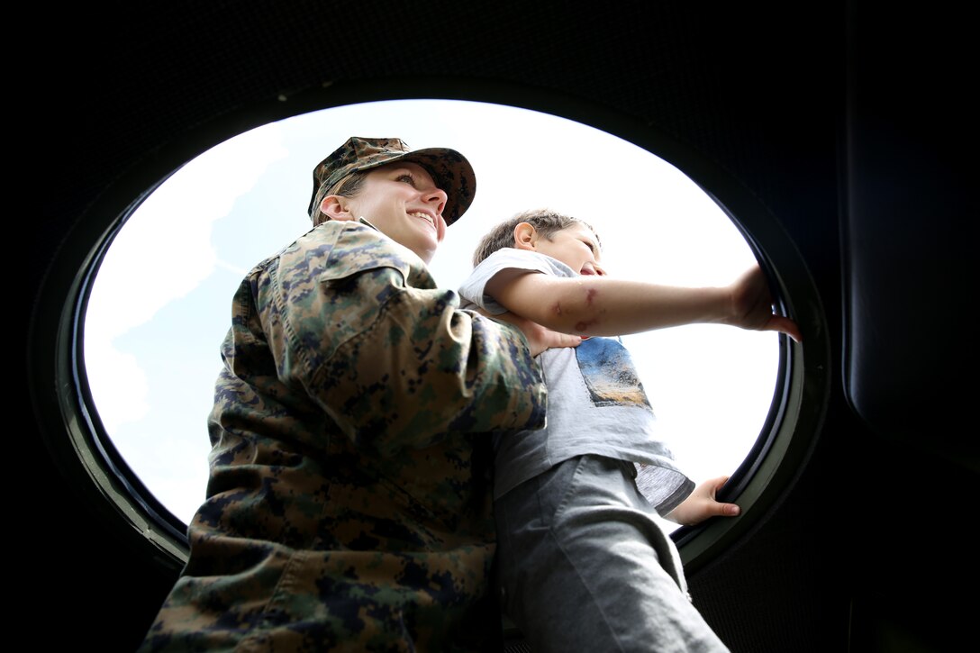 First Lt. Melanie Helmer, the adjutant for Black Sea Rotational Force 14, from 3rd Battalion, 8th Marine Regiment, helps a child look out of the top of a seven-ton truck while Marines and sailors visited a local park in Constanta, Romania during Children’s Day weekend with the community May 31, 2014. Marines and sailors participated in Romania’s Children’s Day with a showcase of standard-issued equipment and military vehicles for children to interact with first-hand. The observation promotes mutual exchange and understanding among children while encouraging actions to benefit and promote the welfare of the nation’s children. (Official Marine Corps photo by Lance Cpl. Scott W. Whiting, BSRF PAO/ Released)