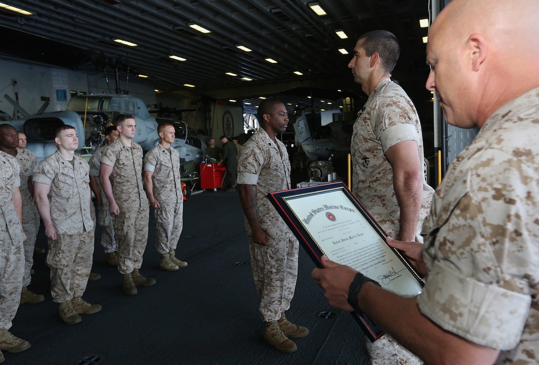 U.S. Marines Corps Gunnery Sgt. Arthur Tolliver, center, 22nd Marine Expeditionary Unit (MEU), maintenance management chief and native of Franklin County, Va., stands at the position of attention as his promotion warrant is read aboard the USS Bataan (LHD 5), at sea, June 1, 2014. Elements of the 22nd MEU, embarked aboard Bataan, are operating in the U.S. 6th Fleet area of operations to augment U.S.  Crisis Response forces in region. (U.S. Marine Corps photo by Lance Cpl. Caleb McDonald/Released)