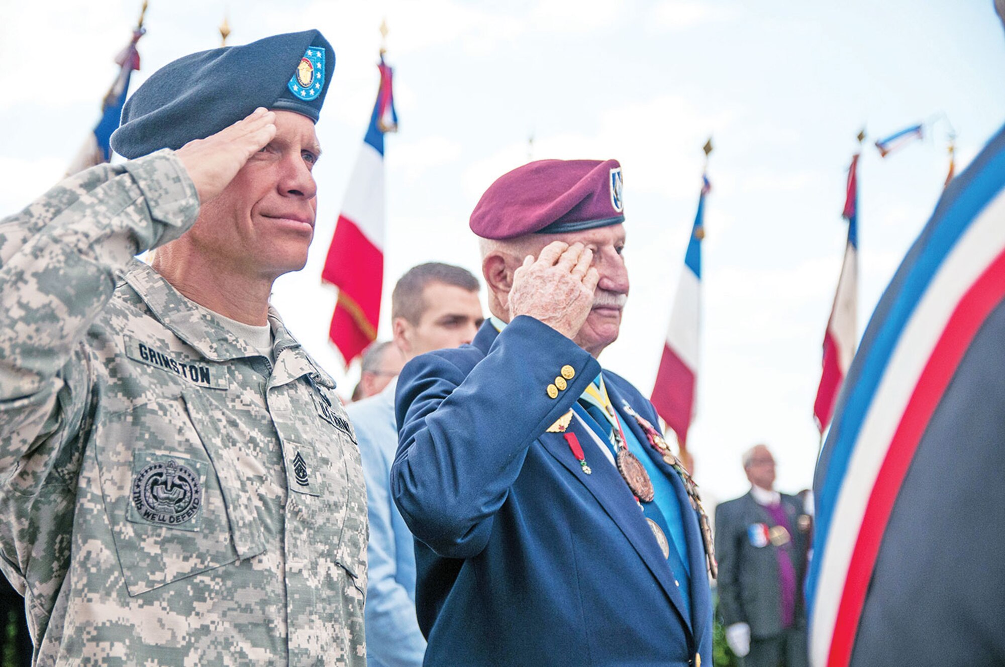 First Inf. Div. Command Sgt. Maj. Michael A. Grinston and retired Command Sgt. Maj. Bill Ryan, a former 1st Inf. Div. Soldier, salute during Taps on June 5 during a ceremony at the “Big Red One” monument at Omaha Beach in Normandy, France. Ryan was wounded as he approached the beach during the D-Day invasion on June 6, 1944. 