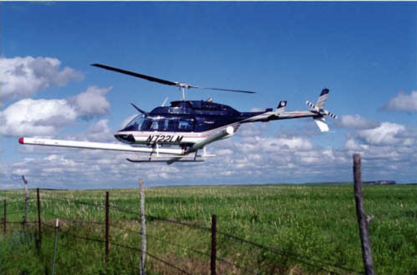 The helicopter in this image is flying an EM/Magnetometer system at a 2-meter altitude to characterize metal distribution over a former impact area.