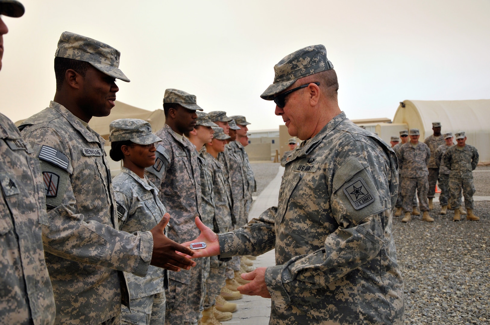 Army Lt. Gen. William Ingram Jr., the director of the Army National Guard, presents a National Guard coin of excellence to Army Sgt. Ferrell Reynolds of the North Carolina National Guard's 1452nd Transportation Company. The trip gave Ingram the opportunity to visit and talk with guardsmen and to see for himself the health and welfare of Army National Guard soldiers in Kuwait.