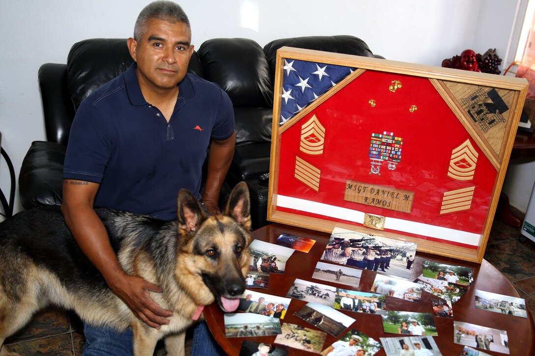 Retired Master Sgt. Daniel Ramos, with his dog Top, displays the shadow box he received upon his retirement from the Marine Corps and photos from various times and places during his career.

Ramos was a combat engineer and the first member of his family to join the armed services.  His son Daniel Ramos Jr. recieved his commission into the Navy May 23, 2014.
