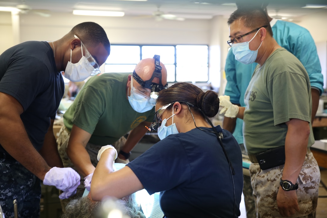 Marine Corps, Army and Navy dental technicians work together to care for a patient at the Kapaa Middle School site, June 19, during Innovative Readiness Training exercise Tropic Care 2014. Kapaa Middle School is one of three main sites that patients can be seen for medical, dental and optometry care provided by the Department of Defense at no cost to the public, providing simultaneous military training for medical personnel. TC14 also allows service members from each branch to combine their expertise in a joint-training environment.   