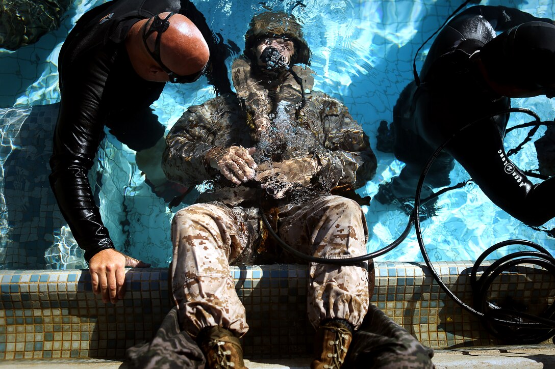 A shallow water egress trainer observes as a Marine goes upside down and attempts to breathe compressed air from an emergency breathing system at the base pool on Marine
Corps Base Hawaii, June 18, 2014. SWET is introductory training that prepares Marines to evacuate an aircraft in the event of an over-water crash. (U.S. Marine Corps photo by Cpl. Matthew Callahan)
