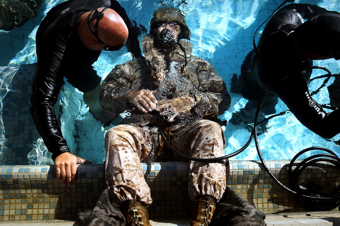 A shallow water egress trainer observes as a Marine goes upside down and attempts to breathe compressed air from an emergency breathing system at the base pool on Marine Corps Base Hawaii, June 18, 2014. SWET is introductory training that prepares Marines to evacuate an aircraft in the event of an over-water crash.