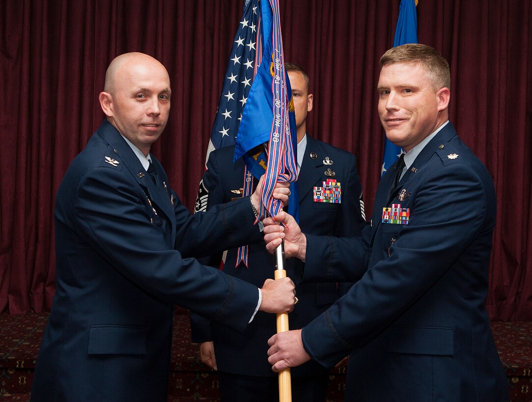 Col. Ron Allen, 90th  Operations Group commander, passes the 319th  Missile Squadron guidon to Lt. Col. Jeremy Olson as he assumes command of the squadron during a change-of-command ceremony in the Trail’s End Club on F.E. Warren Air Force Base, Wyo., June 18, 2014. (U.S. Air Force photo by R.J. Oriez)