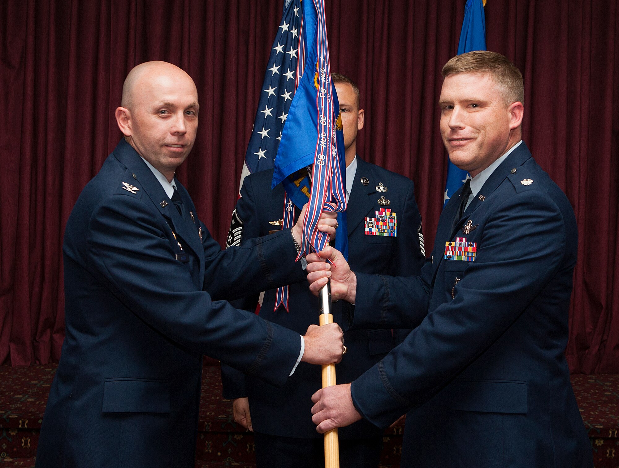 Col. Ron Allen, 90th  Operations Group commander, passes the 319th  Missile Squadron guidon to Lt. Col. Jeremy Olson as he assumes command of the squadron during a change-of-command ceremony in the Trail’s End Club on F.E. Warren Air Force Base, Wyo., June 18, 2014. (U.S. Air Force photo by R.J. Oriez)