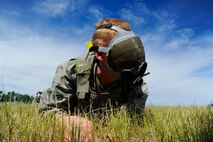 A 341st Security Forces Group member attempts to find an ammo can while wearing a blacked out gas mask during the 3rd Annual Aces Cop Combat Challenge at Malmstrom Air Force Base on June 20.  During this station of the event, four team were required to coordinate with one another to find a hidden object within a pre-determined time period. (U.S. Air Force photo/Airman 1st Class Collin Schmidt) 
