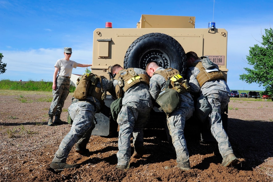 Four Team Malmstrom members attempt to push an up-armored Humvee across the finish line during the 3rd Annual Aces Cop Combat Challenge at Malmstrom Air Force Base on June 20. The Humvee weighed approximately 14,000 pounds and was required to be pushed more than 15 yards up hill and back again. (U.S. Air Force photo/Airman 1st Class Collin Schmidt)