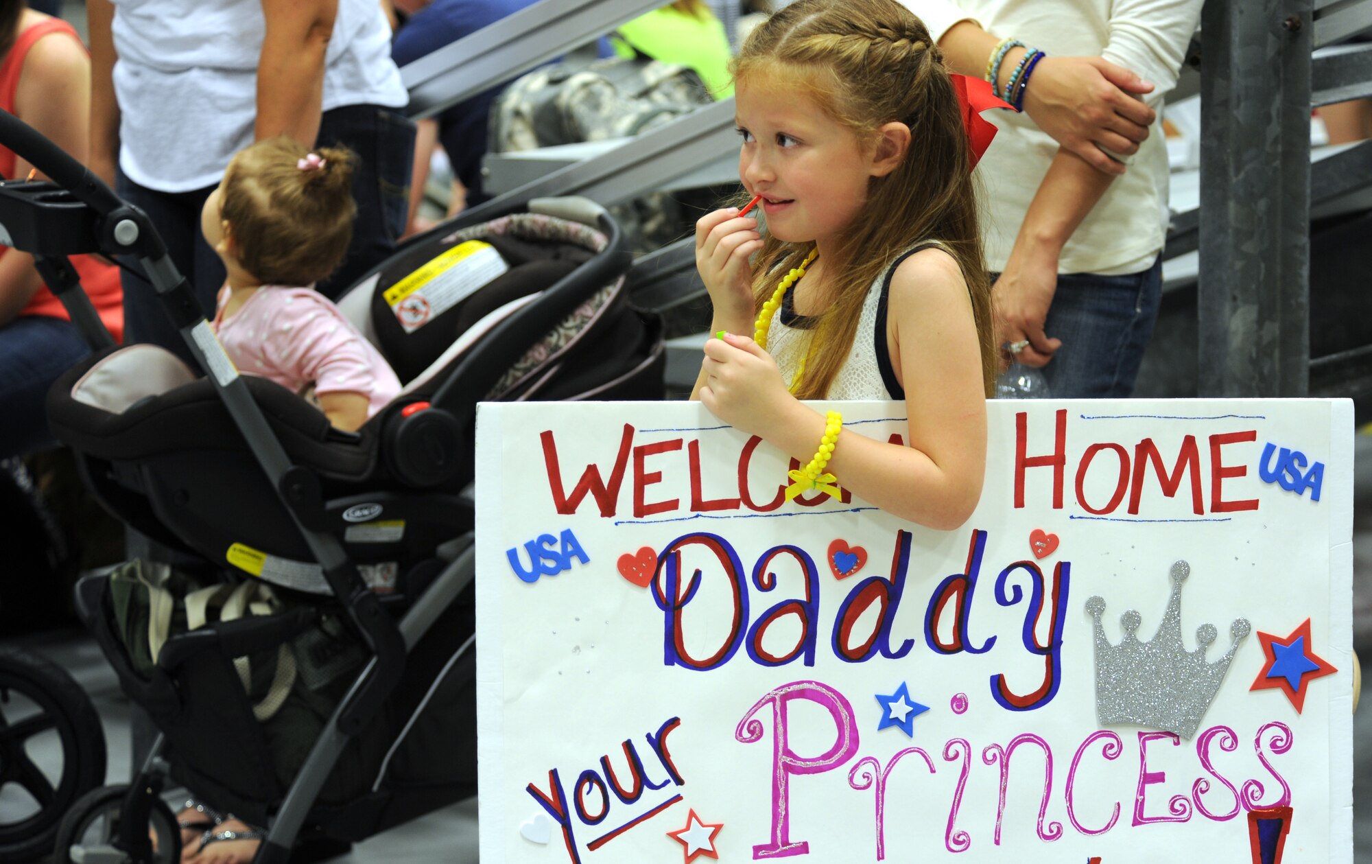 Anna Hudmon, 5, applies lip gloss while she waits for her dad, Staff Sgt. James Hudmon, 901st Special Operations Aircraft Maintenance Squadron maintainer, during Operation Homecoming at Hurlburt Field, Fla., June 21, 2014. Hudmon was one of the 60 Hurlburt members who returned from an overseas deployment. (U.S. Air Force photo/Staff Sgt. Melanie Holochwost) 