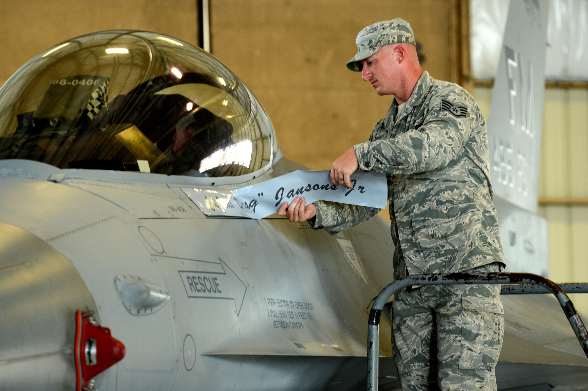 U.S. Staff Sgt. Gregory Burroughs, 495th Fighter Group tactical aircraft maintainer, removes the name of the 495th FG’s outbound commander from an F-16CJ Fighting Falcon during a change of command ceremony at Shaw Air Force Base, S.C., June 20, 2014. Col. Juris Jansons relinquished command to Col. James McCune. (U.S. Air Force photo by Airman 1st Class Jensen Stidham/Released)