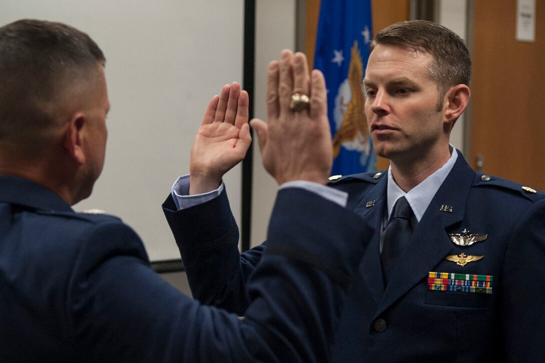 U.S. Air Force Maj. Aaron Bohl, recites the oath during a Pinning On ceremony at Barksdale Air Force Base, La., June 23, 2014.  Bohl is a former Marine helicopter pilot, and now a B-52 pilot. (U.S. Air Force photo by Master Sgt. Jeff Walston/Released)