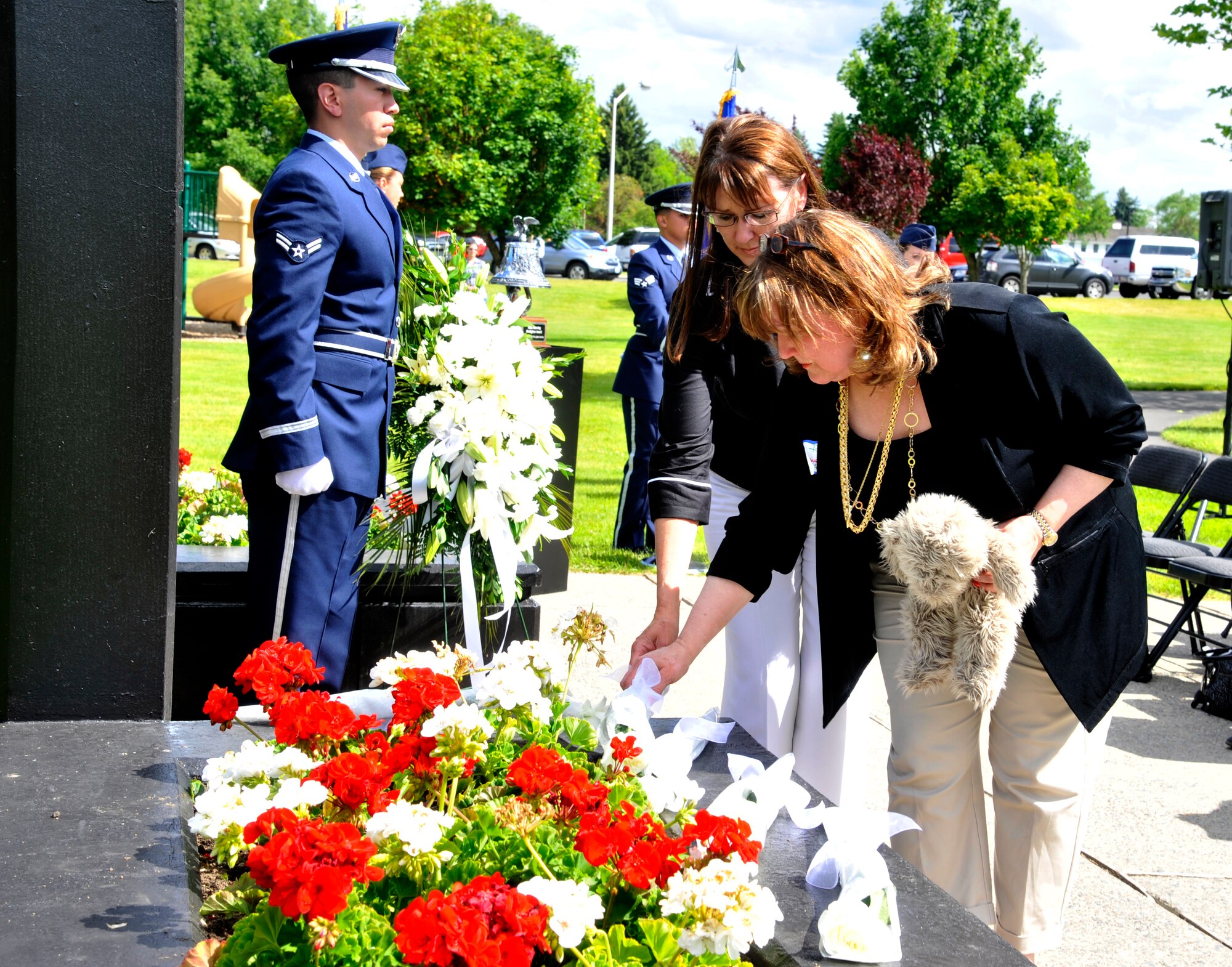 Friends and family members of those affected by the hospital shooting that took place at Fairchild Air Force Base 20 years ago place flowers on the memorial site June 20, 2014. A ceremony was held in remembrance of the lives lost that day, when an active-shooter opened fire in the base hospital. (U.S. Air Force photo by Senior Airman Mary O'Dell/Released)