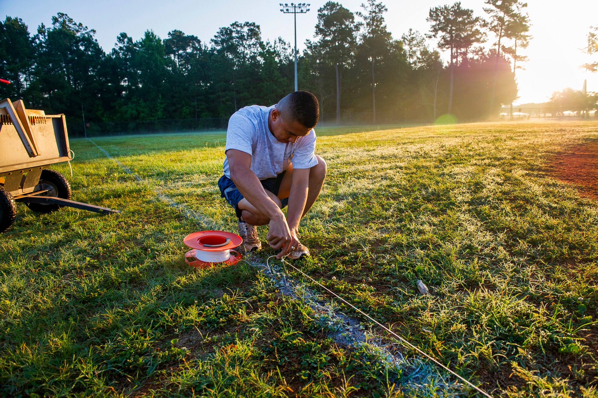 Staff Sgt. Lakan Ello, 628th Force Support Squadron fitness specialist, stakes down a chalk line June 18, 2014, at Joint Base Charleston, S.C. New chalk lines are put down every game day to keep the field maintained for the players. (U.S. Air Force photo/Senior Airman George Goslin)