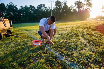Staff Sgt. Lakan Ello, 628th Force Support Squadron fitness specialist, stakes down a chalk line June 18, 2014, at Joint Base Charleston, S.C. New chalk lines are put down every game day to keep the field maintained for the players. (U.S. Air Force photo/Senior Airman George Goslin)