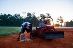 Staff Sgt. David Johnson, 628th Force Support Squadron sports program director, cleans a base June 18, 2014, at Joint Base Charleston, S.C. The infields are raked and the bases are cleaned after being watered to prepare for the day's game. (U.S. Air Force photo/Senior Airman George Goslin)