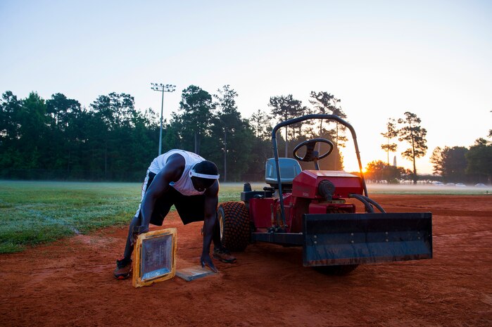 Staff Sgt. David Johnson, 628th Force Support Squadron sports program director, cleans a base June 18, 2014, at Joint Base Charleston, S.C. The infields are raked and the bases are cleaned after being watered to prepare for the day's game. (U.S. Air Force photo/Senior Airman George Goslin)