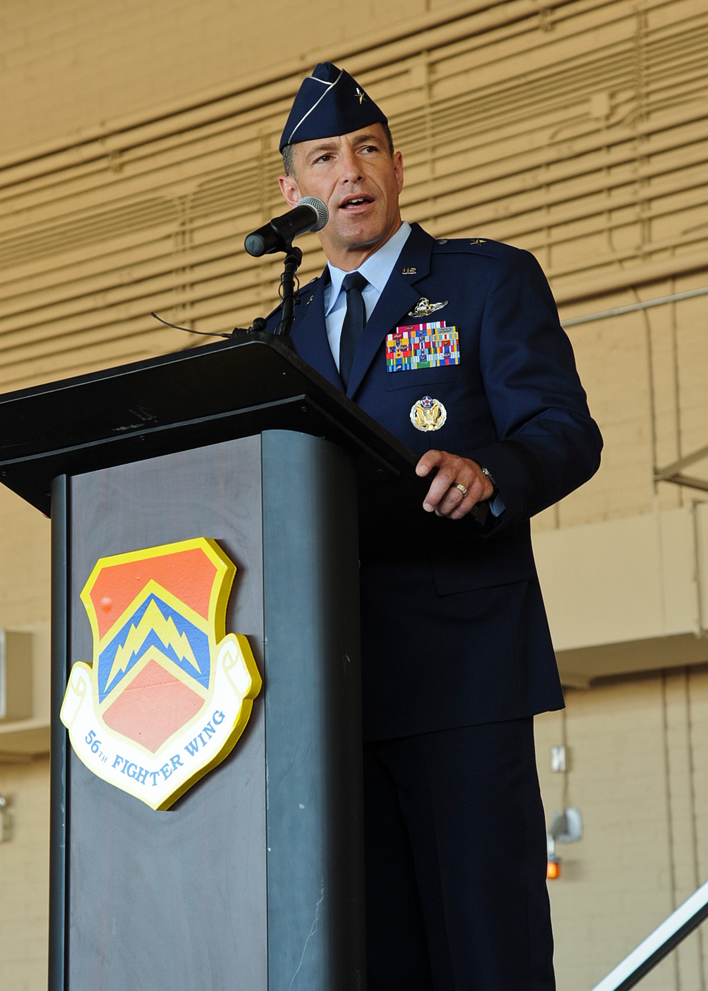 Brig. Gen. Scott Pleus, 56th Fighter Wing commander, speaks to the audience after assuming command of the wing at a ceremony on Luke Air Force Base on June 20. The general is accompanied at Luke by his wife, Jennifer, and their two sons and daughter: Jared, 16; Jack, 11; and Jamie, 14. “Luke is a family, and Jennifer and I are proud to be part of it,” he said. (U.S. Air Force photo/Staff Sgt. Darlene Setlmann)