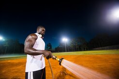 Staff Sgt. David Johnson, 628th Force Support Squadron sports program director, waters an infield, June 18, 2014, at Joint Base Charleston, S.C. The fields are watered to soften them up to give players more traction and prevent injury. (U.S. Air Force photo/Senior Airman George Goslin)