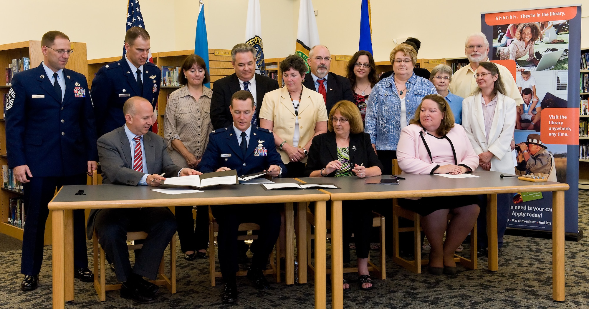 Delaware Governor Jack Markell, seated left, and Col. Kevin Gordon, seated second from left, 436th Airlift Wing vice commander, Dover Air Force Base, Del., sign a Memorandum of Understanding, June 23, 2014, at the Kent County Public Library, Dover, Del. The MOU integrates the materials of the Dover AFB Library through a "floating collection," which will be made available for use by all Delawareans through Delaware libraries statewide. (U.S. Air Force photo/Roland Balik)