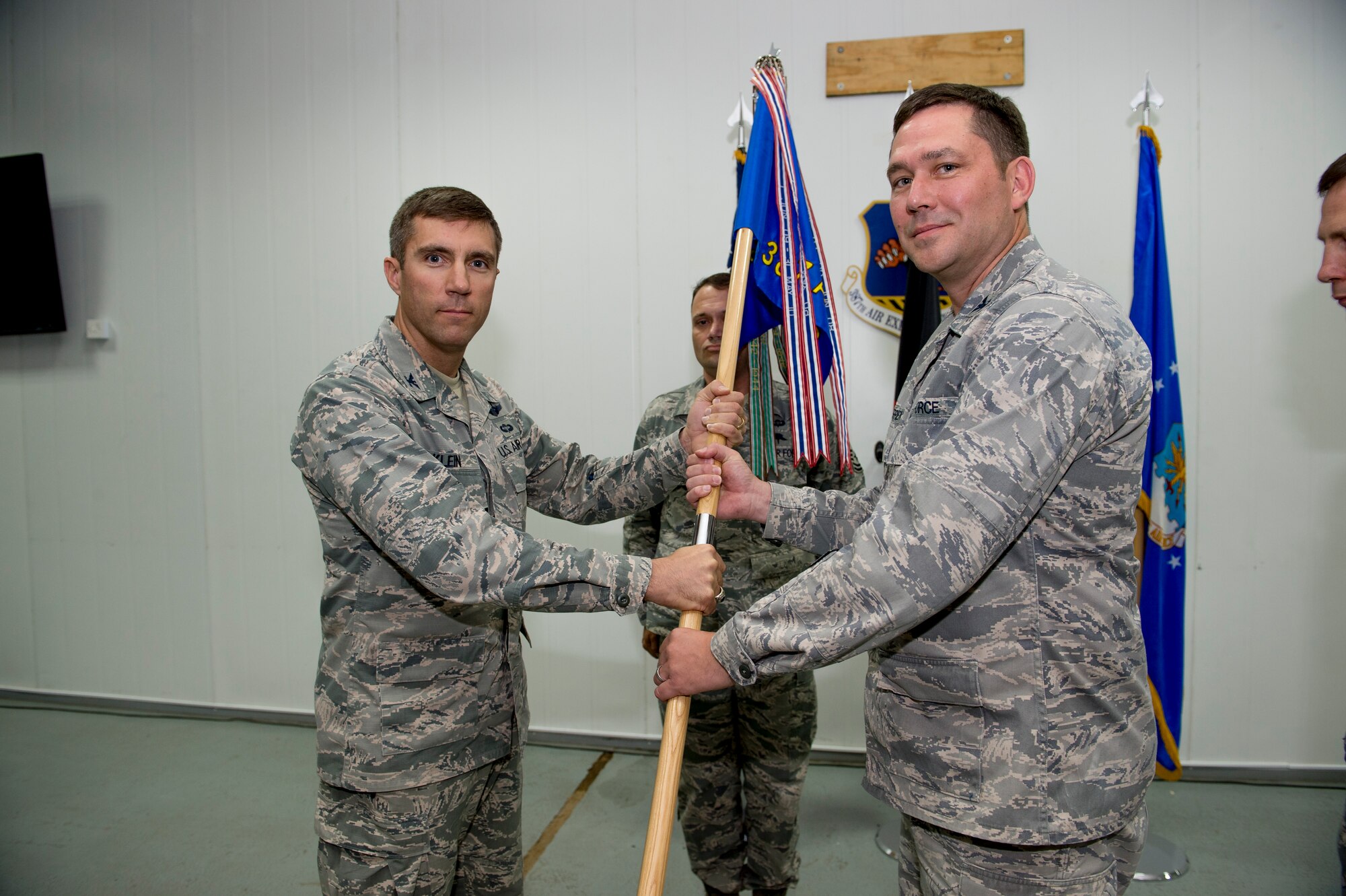 U.S. Air Force Col. John Klein, 386th Air Expeditionary Wing commander, hands the 387th Air Expeditionary Group guidon to Col. Kevin Therrien during a change of command ceremony June 22, 2014 at an undisclosed location in Southwest Asia. Therrien comes from the Pentagon in Arlington, Virginia where he served as the joint staff, strategic plans and policy, north and west Africa division chief. (U.S. Air Force photo by Staff Sgt. Jeremy Bowcock)