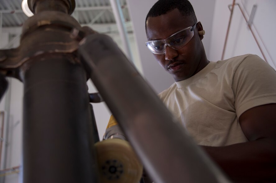 Airman 1st Class Ryan Motte, 423nd Maintenance Squadron Aerospace Ground Equipment mechanic, sands the stickers off a 10 ton jack in preparation to be painted at Creech Air Force Base, Nev., June 18, 2014. AGE maintains all the equipment necessary to power or repair the MQ-1 Predator and MQ-9 Reaper remotely piloted aircraft on home station and deployed locations. (U.S. Air Force photo by Airman 1st Class Christian Clausen/Released)