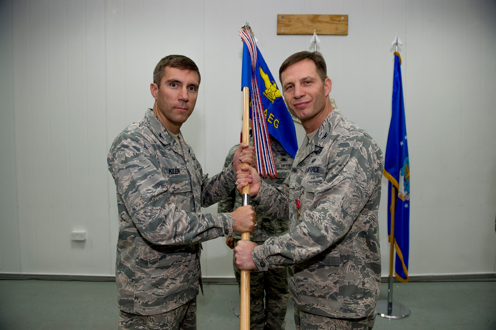 U.S. Air Force Col. James Dryjanski hands the 387th Air Expeditionary Group guidon to Col. John Klein, 386th Air Expeditionary Wing commander, during a change of command ceremony June 22, 2014 at an undisclosed location in Southwest Asia. Dryjanski relinquished command of the 387th AEG to Col. Kevin Therrien and will be moving on to command the 314th Airlift Wing at Little Rock Air Force Base, Arkansas. (U.S. Air Force photo by Staff Sgt. Jeremy Bowcock)